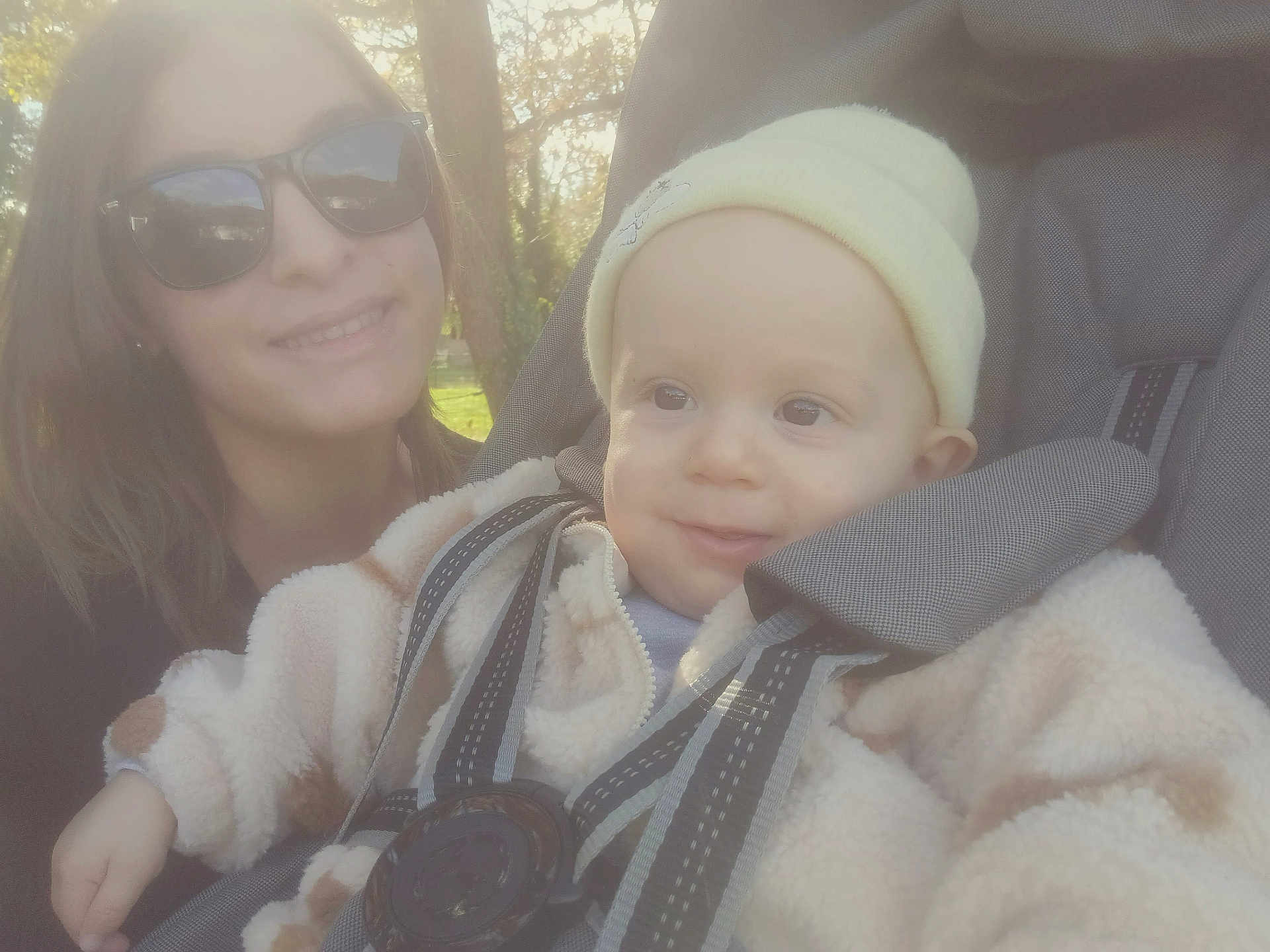 Maël participe au concours pour gagner de l'argent avec cette photo : baby, child, woman, sunglasses, stroller, outdoor, nature, trees, smile, jacket, hat, sunlight, daylight, park, person, face, seatbelt, happy, casual, portrait