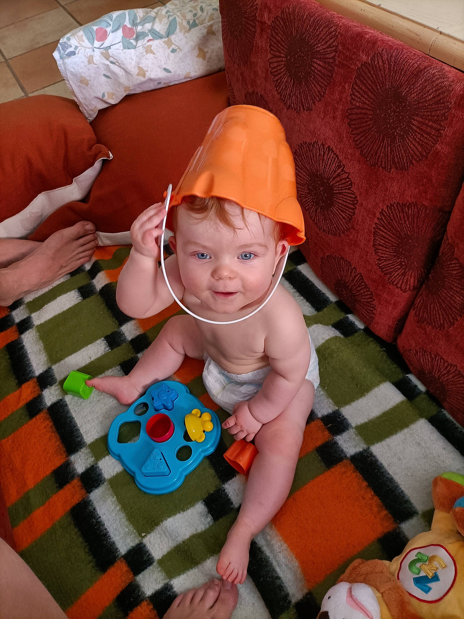 Lyne a rejoint le concours — aidez-le/la à gagner de superbes lots ! baby, baby_products, baby_toddler_clothing, baby_toys, child, comfort, flooring, fun, happy, lap, linens, orange, pattern, person, play, room, sitting, smile, sock, textile