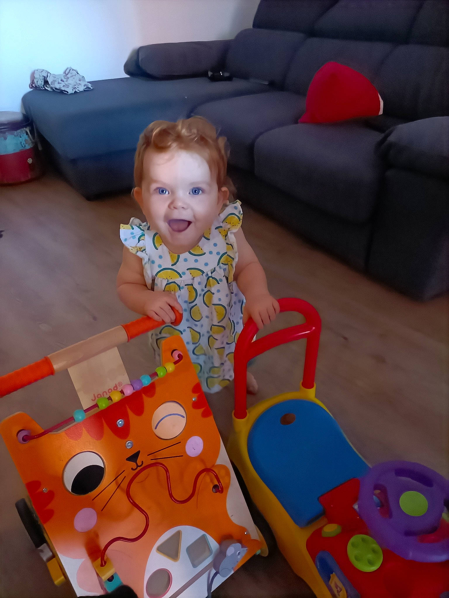 Lyne participe au concours pour gagner de l'argent avec cette photo : baby, baby_playing_with_toys, baby_toddler_clothing, child, comfort, couch, dress, floor, flooring, fun, furniture, living_room, people, person, pink, play, product, room, sitting, smile