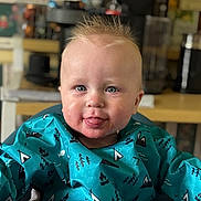 Rowan joined the competition — help win amazing prizes! baby, child, tongue_out, blue_eyes, spiky_hair, bib, high_chair, indoor, kitchen, smiling, face, person, clothing, seat, cute, young, infant, portrait, happy, feeding_time