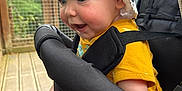 Tobias a rejoint le concours — aidez-le/la à gagner de superbes lots ! baby, child, stroller, hat, yellow_shirt, smiling, happy, face, blue_eyes, barefoot, outdoor, wooden_deck, greenery, seatbelt, person, infant, cute, sunhat, expression, closeup