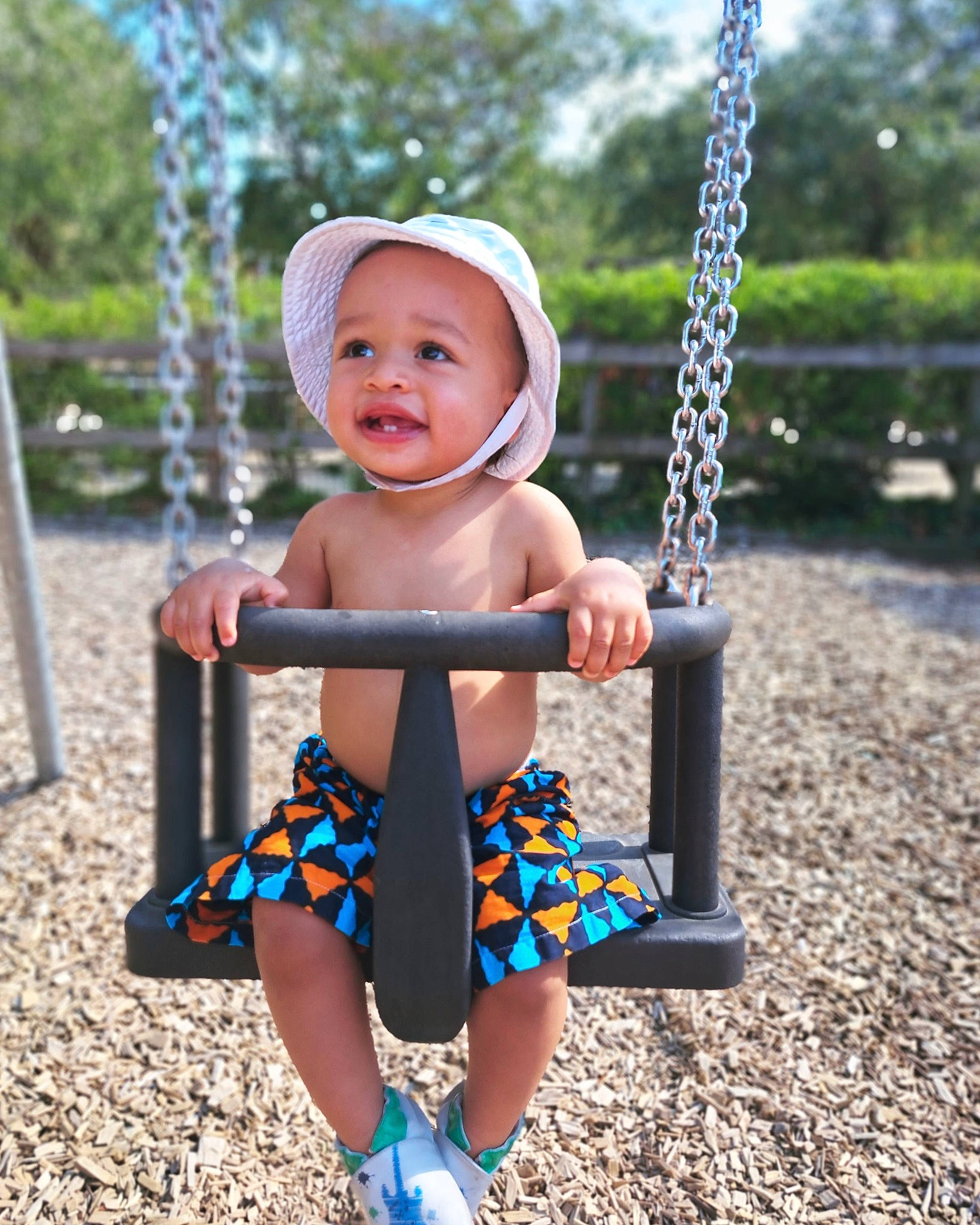 éden a rejoint le concours — aidez-le/la à gagner de superbes lots ! baby, baby_toddler_clothing, blue, city, face, facial_expression, fun, grass, happy, headwear, leisure, person, pink, playground, product, public_space, recreation, smile, swing, toddler