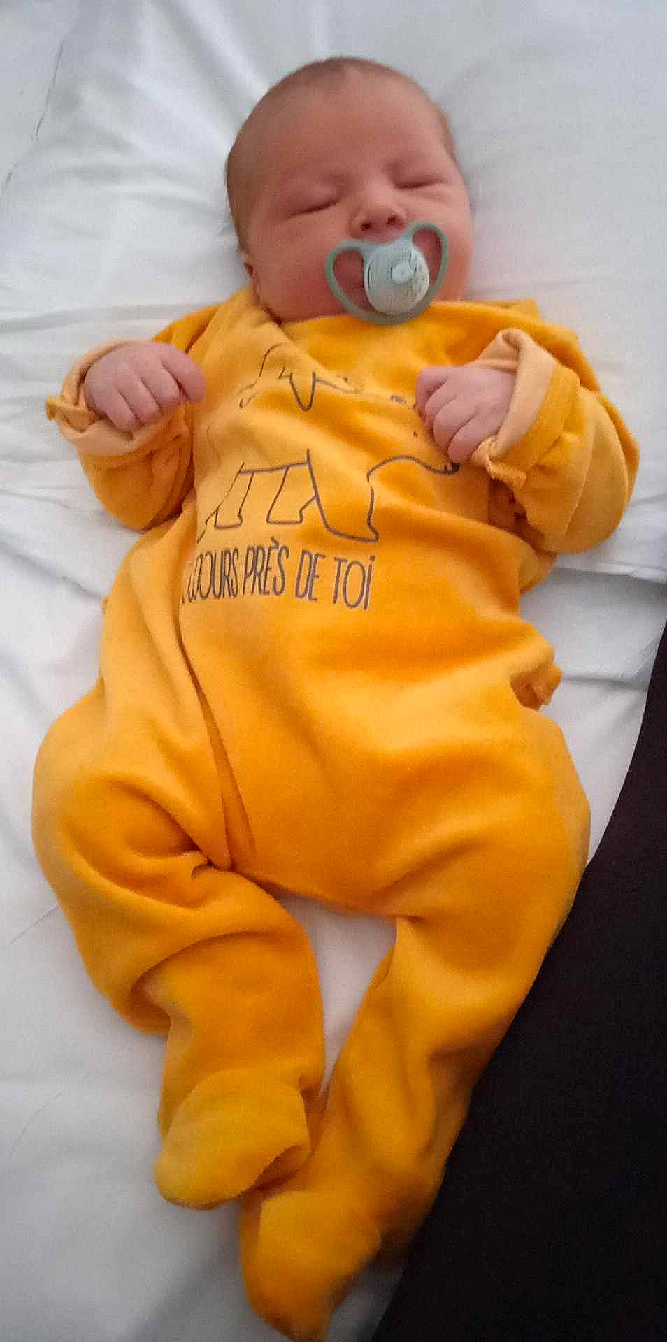Diego participe au concours pour gagner de l'argent avec cette photo : arm, baby, baby_toddler_clothing, child, comfort, drinkware, finger, font, gesture, hand, happy, human_body, jacket, linens, orange, person, sleeve, sportswear, t_shirt, thumb