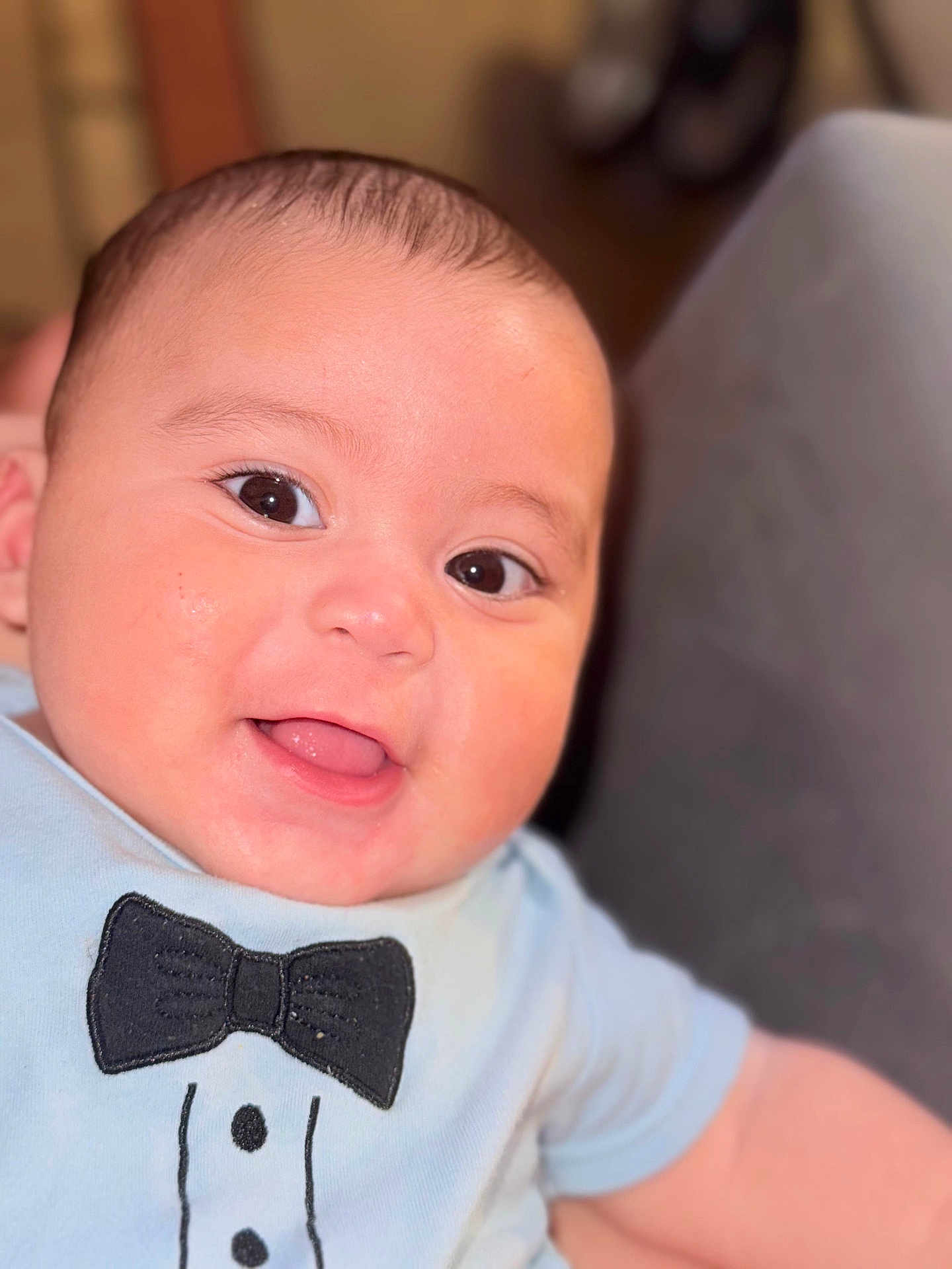 Alexis is registered to the contest to win money with this photo: baby, smiling, face, infant, child, cute, portrait, clothing, blue_shirt, bowtie, happy, skin, eyes, mouth, expression, indoor, person, closeup, soft_light, blurred_background