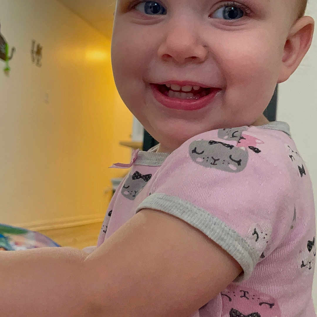 Arianna is registered to the contest to win money with this photo: baby, blonde, bodypart, clothing, dress, face, finger, hair, hand, happy, head, indoors, interiordesign, mouth, person, photography, portrait, smile, t_shirt, teeth
