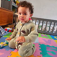 Abel a rejoint le concours — aidez-le/la à gagner de superbes lots ! toddler, child, curly_hair, knitted_clothing, hedgehog_design, play_mat, colorful, toy, crib, indoor, floor, cute, smile, child_room, furniture, baby, person, crawling, home, portrait