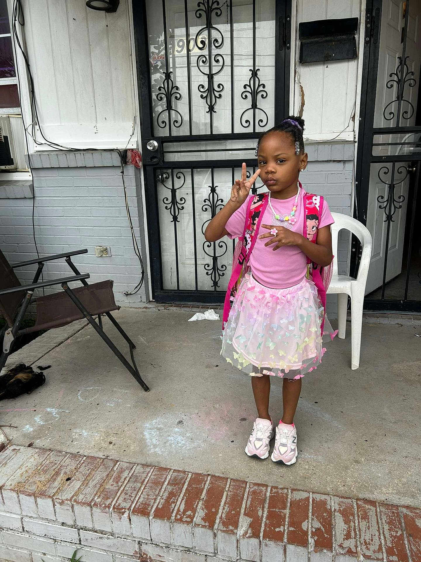 Zari'Yannah Jones joined the competition — help win amazing prizes! child, girl, peace_sign, pink_clothing, tutu_skirt, backpack, jewelry, porch, door, iron_gate, concrete, chalk_drawing, chair, sneakers, expression, outdoor, steps, brick, window, casual