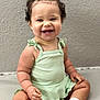 baby, child, smiling, curly_hair, bow, green_dress, sitting, pink_shoes, white_socks, floor, wall, cute, happy, portrait, infant, indoors, person, plump, fashion, toddler