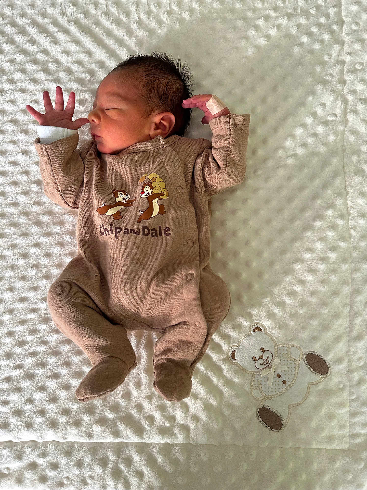 Liam a rejoint le concours — aidez-le/la à gagner de superbes lots ! newborn, baby, infant, sleeping, onesie, chip_and_dale, footed_pajamas, blanket, textured_blanket, applique_teddy_bear, bandage_on_hand, dark_hair, peaceful, portrait, lying_down, small_hands, cozy, soft_lighting, nursery, close_up