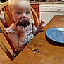 Maylee is registered to the contest to win money with this photo: toddler, child, cupcake, chocolate, kitchen, wooden_table, wooden_chair, crumbs, plate, cabinet, dishwasher, appliance, person, food, eating, indoor, sitting, long_sleeve_shirt, face, cute