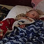 child, sleeping, blanket, plush_toy, pillow, bed, cozy, indoors, resting, comfort, soft, warm, cute, peaceful, nap, furniture, person, clothing, head, hand