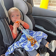Maylee is registered to the contest to win money with this photo: black, blanket, blue, brick_wall, car_interior, car_seat, casual, child, clothing, drink_container, gray, indoor, orange, person, seatbelt, shoes, toddler, vehicle, window, yellow