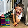 basket, boy, bracelet, brown_hair, building_blocks, candid, child, colorful, cute, floor, fun, happy, indoor, play, shelf, smiling, tongue_out, toys, white_shirt, wooden_floor