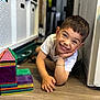 boy, casual_clothing, child, colorful, face, floor, hand, happy, indoor, magnetic_tiles, play, portrait, shelf, short_hair, smile, storage, toy, white_shirt, wooden_floor, young