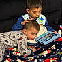 blanket, child, children, christmas, clothing, couch, cozy, face, family, furniture, hand, head, holiday, indoor, pajamas, screen, sibling, tablet, toy, watching