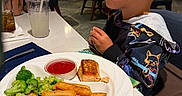 Elijah is registered to the contest to win money with this photo: boy, broccoli, child, clothing, cute, dining, drink, food, fries, glass, indoor, ketchup, people, plate, restaurant, salmon, seated, straw, table, waiting