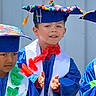 blue, cap, celebration, child, children, clapping, colorful, decorated_cap, event, festive, gown, graduation, happy, outdoor, person, portrait, sash, smiling, toddler, young