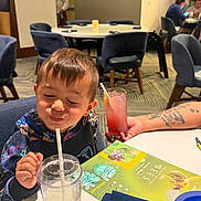 Elijah joined the competition — help win amazing prizes! child, boy, drink, straw, table, restaurant, menu, chair, tattoo, person, indoor, happy, casual, food, beverage, smile, hair, clothing, dining, family