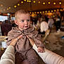 Bobbie is registered to the contest to win money with this photo: baby, child, hands, clothing, heart_pattern, indoor, string_lights, blurred_background, people, warm_lighting, cute, portrait, person, infant, sweater, pink, brown, holding, face, expression