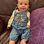 Bobbie joined the competition — help win amazing prizes! baby, child, denim_overalls, floral_embroidery, couch, leather, purple_cushion, smiling, happy, indoor, infant, sitting, cute, person, clothing, foot, hand, face, portrait, cozy
