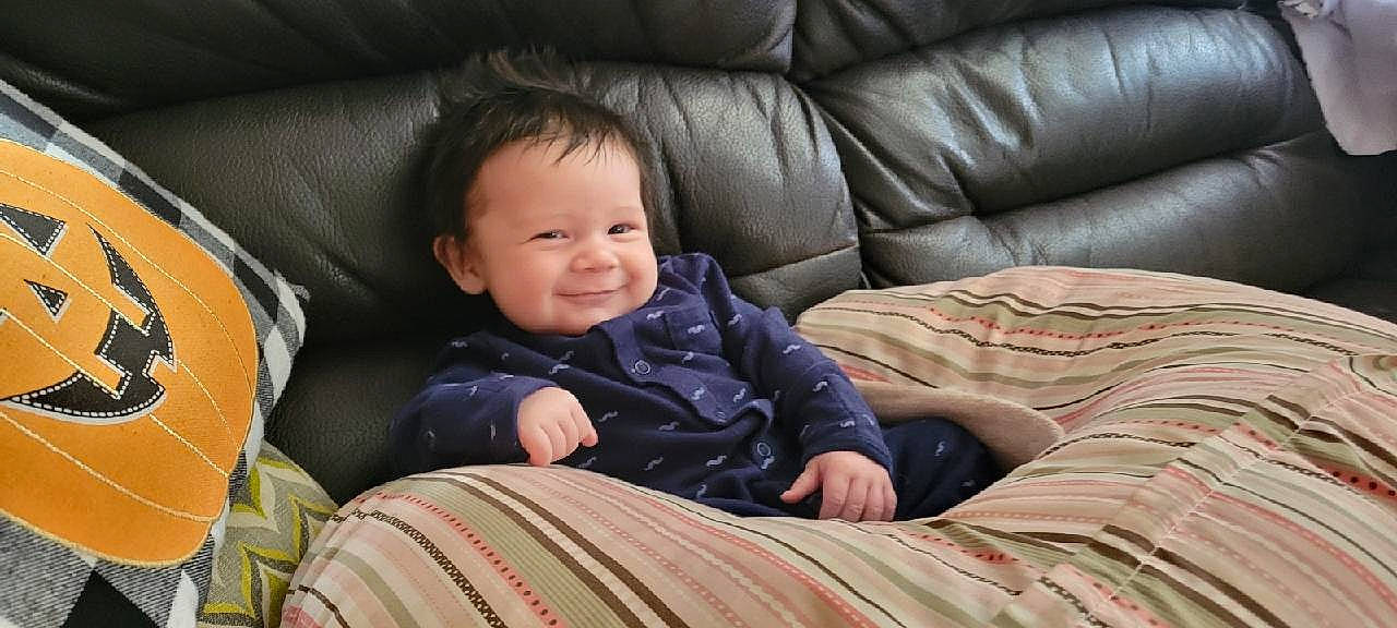 Jaxson is registered to the contest to win money with this photo: baby, baby_toddler_clothing, car_seat, cheek, child, comfort, couch, face, flooring, fun, grass, joy, linens, person, room, sitting, sleeve, smile, textile, toddler