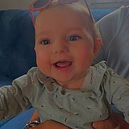 Djena participe au concours pour gagner de l'argent avec cette photo : adult, baby, blue_couch, child, closeup, clothing, curtains, face, hands, happy, holding, indoor, infant, long_sleeves, person, pink, portrait, smiling, sunglasses, window