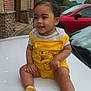 Jhlani Dockins is registered to the contest to win money with this photo: toddler, child, yellow_clothing, winnie_the_pooh, car, white_car, red_car, outdoor, smiling, cute, baby_socks, brick_building, sidewalk, cloudy_sky, person, happy, sitting, portrait, hair_bow, earrings
