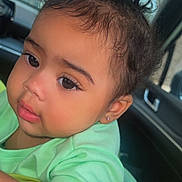 Jhlani Dockins is registered to the contest to win money with this photo: baby, child, curly_hair, green_shirt, earring, close_up, car_interior, window, natural_light, face, skin, person, cute, infant, young_child, portrait, expression, eye, nose, mouth