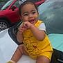 baby, child, smiling, yellow_clothing, sitting, car, hood, outdoor, cloudy_sky, red_car, playful, happy, cute, person, sock, shorts, toddler, winnie_the_pooh, vehicle, daytime