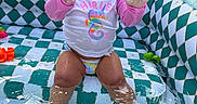 Aylani Michelle is registered to the contest to win money with this photo: toddler, child, inflatable_pool, water, splashing, pink_hat, swimsuit, toys, colorful, outdoor, summer, playful, happy, sitting, water_toys, backyard, sunlight, patterned_pool, curious, baby