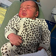Lyse participe au concours pour gagner de l'argent avec cette photo : newborn, baby, sleeping, infant, leopard_print, onesie, clothing, hand, face, person, indoor, bed, blanket, plush_toys, nursery, soft_lighting, cute, peaceful, resting, child