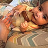Brookelyn is registered to the contest to win money with this photo: baby, infant, child, bottle, feeding, bed, bedding, blanket, pillow, patterned_fabric, indoors, home, lying_down, wide_eyes, hands, adult_hand, portrait, casual_photo, sleepwear, family