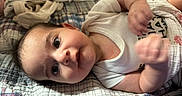 Brookelyn is registered to the contest to win money with this photo: baby, infant, child, lying_down, wide_eyes, looking_at_camera, face, smiling, white_clothing, onesie, blanket, plaid, bed, cozy, indoor, portrait, close_up, hands, bedding, soft_lighting