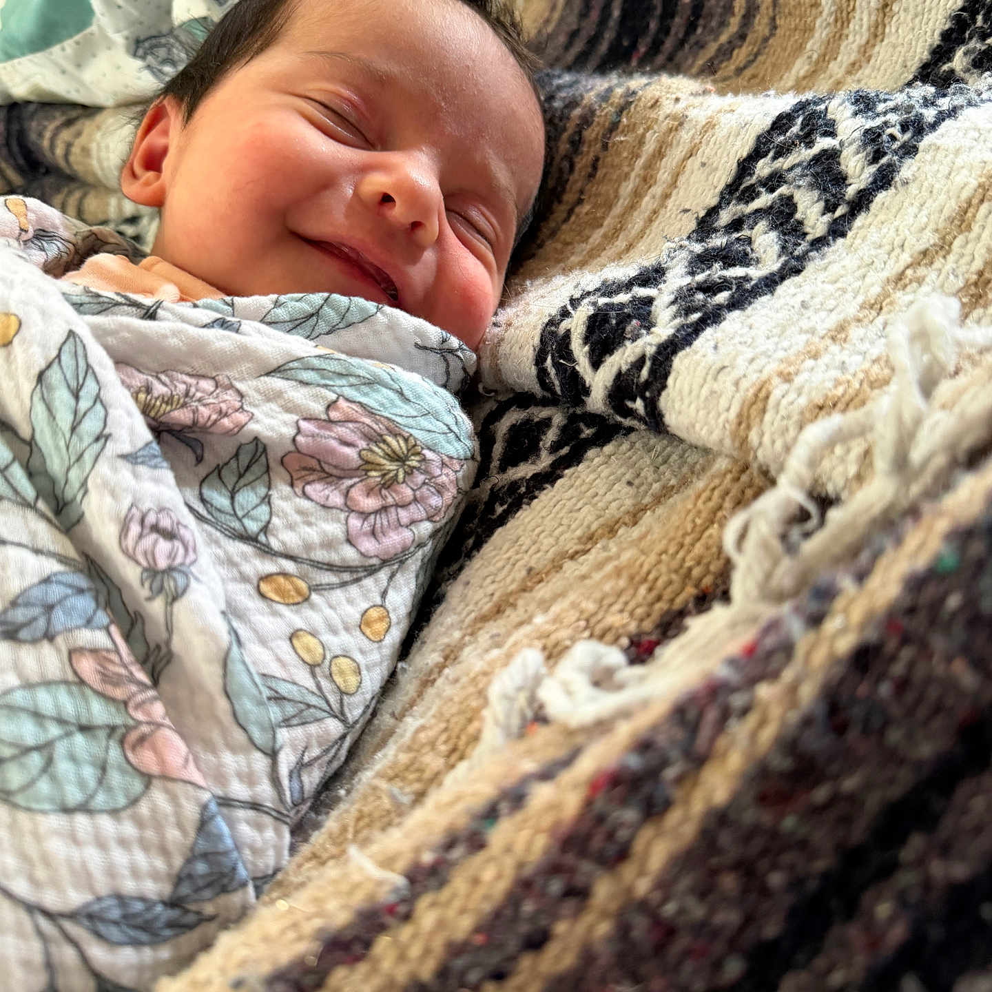 Brookelyn joined the competition — help win amazing prizes! baby, newborn, smiling, wrapped, blanket, floral_pattern, cozy, woven_fabric, texture, sleeping, face, head, infant, person, comfort, soft, closeup, indoors, peaceful, resting