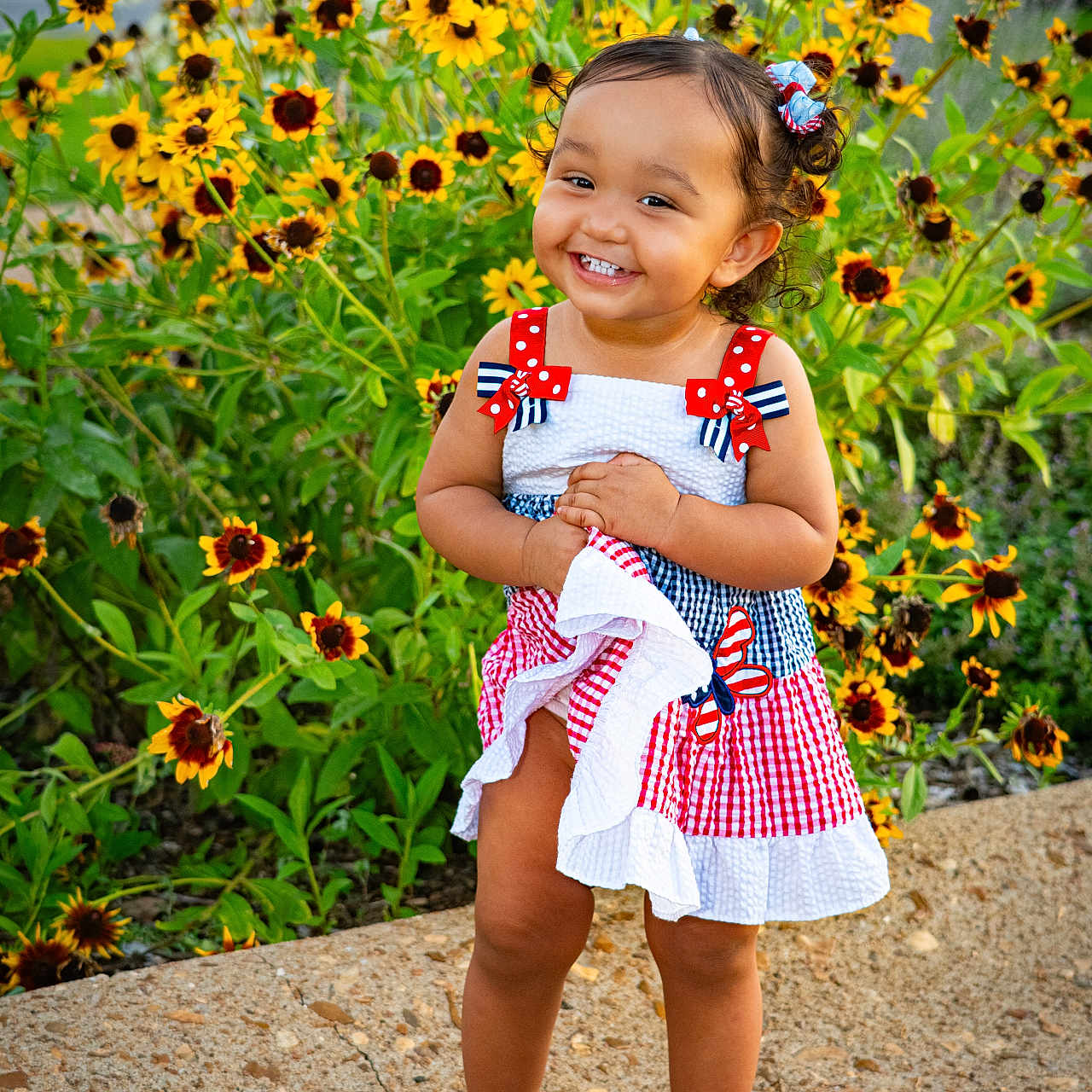 Malahney joined the competition — help win amazing prizes! barefoot, blue, bows, child, cute, dress, flowers, garden, greenery, happy, nature, outdoor, portrait, red, smiling, standing, sunlight, toddler, white, yellow_flowers