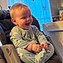 Maylan a rejoint le concours — aidez-le/la à gagner de superbes lots ! baby, child, high_chair, pajamas, smiling, happy, indoor, furniture, seatbelt, curtain, blue, family_photos, cabinet, cozy, cute, infant, person, expression, joy, soft_lighting