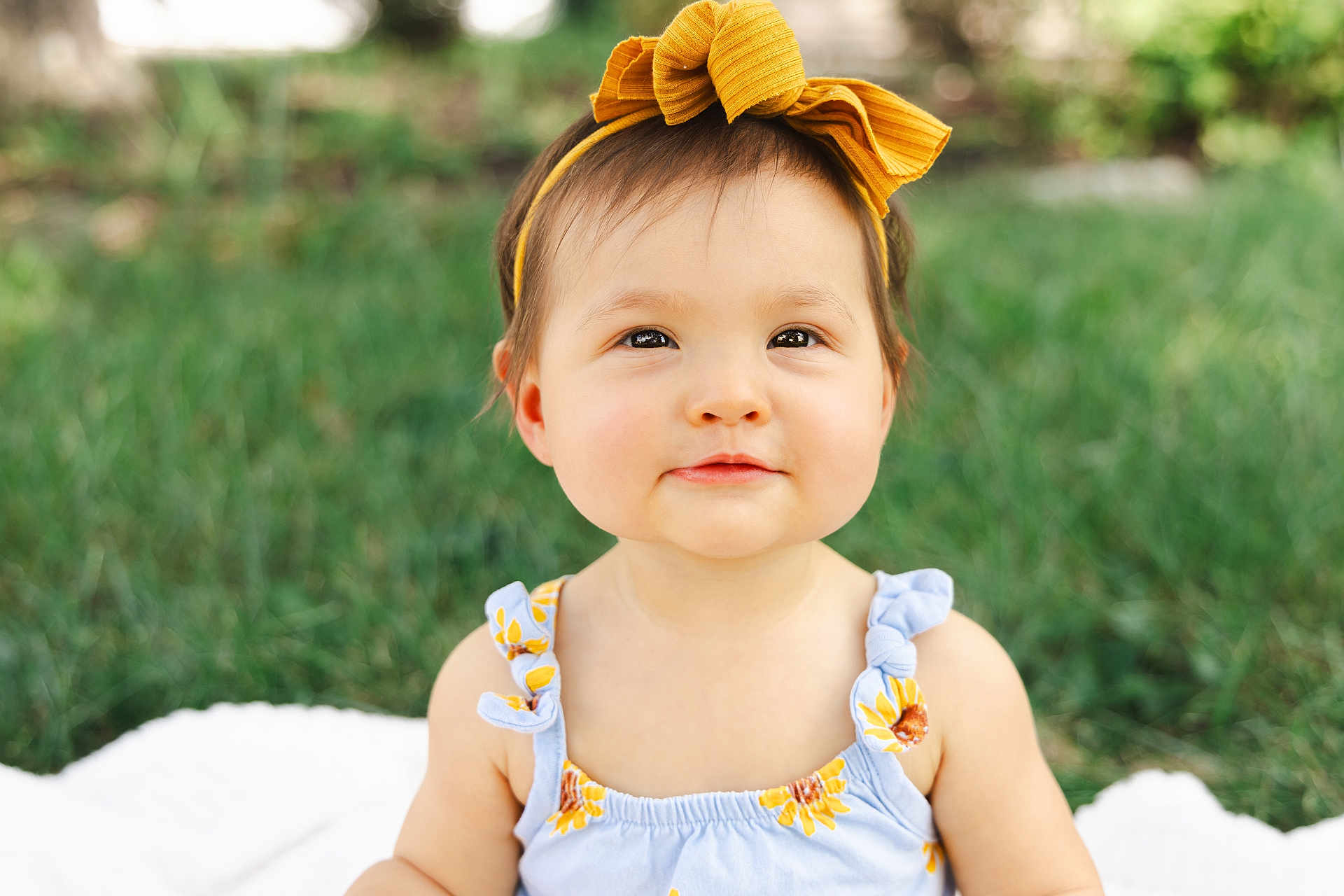 Lylah Ruth joined the competition — help win amazing prizes! baby, child, girl, portrait, outdoor, grass, headband, yellow_bow, smile, dress, sunflower_pattern, blanket, cute, happy, infant, summer, nature, skin, face, person