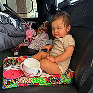 Lylah Ruth is registered to the contest to win money with this photo: toddler, child, car_seat, toy, blanket, quilt, sippy_cup, interior, car, leather_seat, american_flag, window, baby, person, clothing, foot, hand, seat, comfortable, indoor