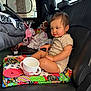toddler, child, car_seat, toy, blanket, quilt, sippy_cup, interior, car, leather_seat, american_flag, window, baby, person, clothing, foot, hand, seat, comfortable, indoor
