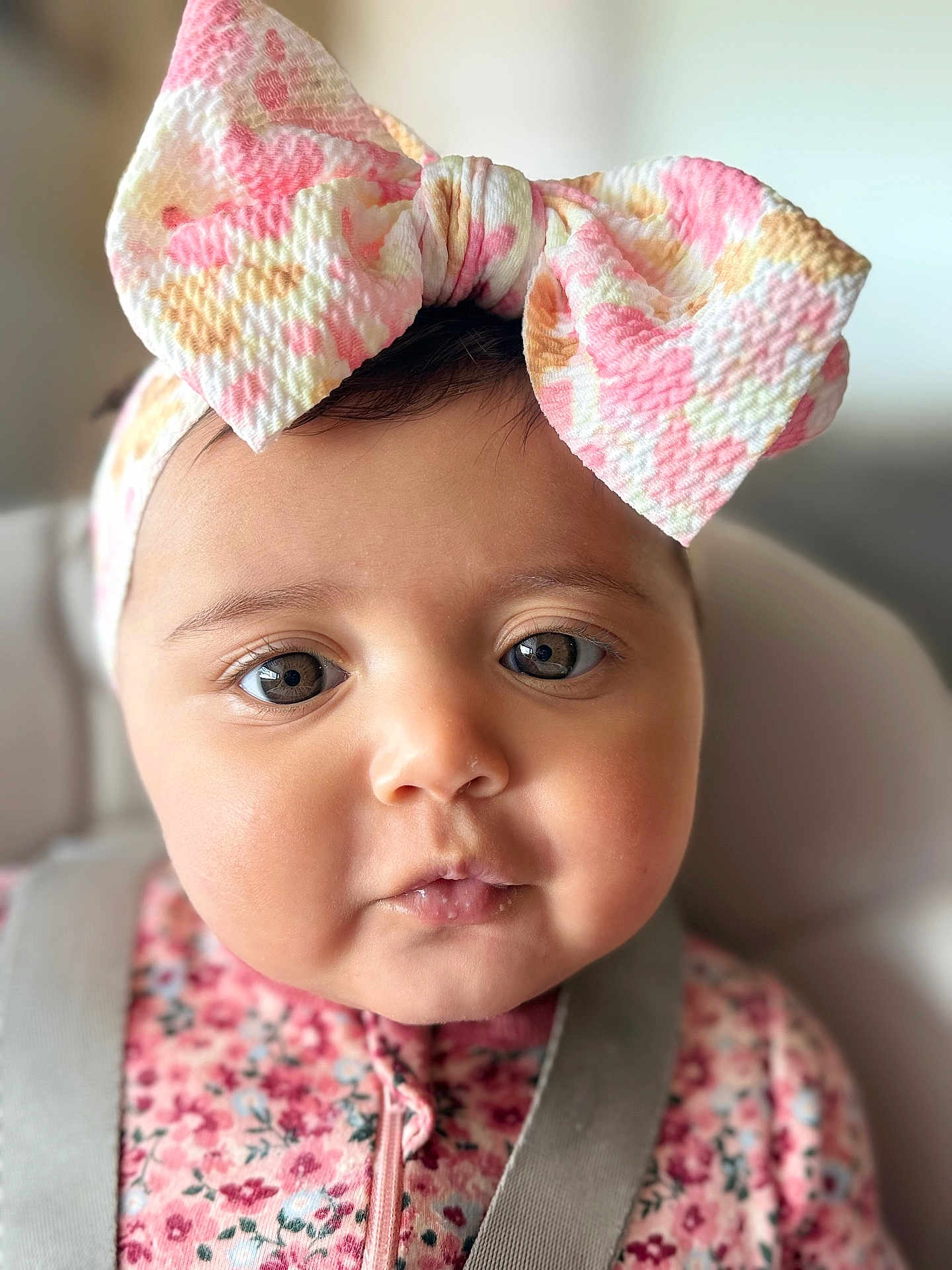 Kinslee Mae is registered to the contest to win money with this photo: baby, infant, headband, bow, close_up, portrait, big_bow, pink, floral, onesie, highchair, chubby_cheeks, eyes, face, eyelashes, soft_lighting, bokeh, indoor, adorable, neutral_background