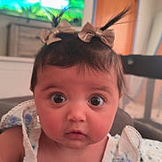 Kinslee Mae joined the competition — help win amazing prizes! baby, infant, child, portrait, closeup, big_eyes, surprised, hair_bows, dress, floral_print, indoor, television, dresser, door, furniture, couch, food_on_face, sitting, person, cute