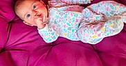 Ellianna is registered to the contest to win money with this photo: baby, infant, child, onesie, floral_pattern, pink_chair, cushion, thumb_sucking, relaxing, indoor, cute, small_person, comfort, portrait, seated, soft_furniture, colorful, young, head, face