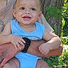 baby, child, smiling, blue_clothing, outdoor, greenery, tree, person, arm, hand, nature, sunlight, skin, shorts, tattoo, watch, happy, summer, casual, portrait