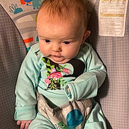 Liliana joined the competition — help win amazing prizes! baby, infant, child, bouncer, clothing, mint_green, animal_print, rainbow, cute, indoors, person, young_child, seat, playful, soft_lighting, toddler, face, hair, looking_down, comfort