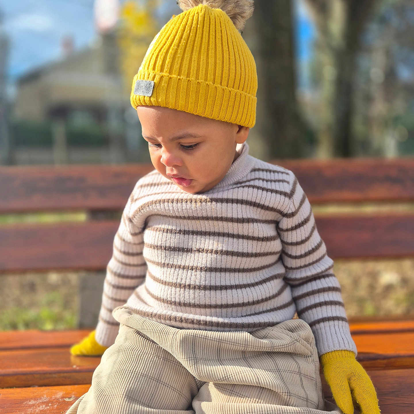Dream a rejoint le concours — aidez-le/la à gagner de superbes lots ! autumn, beige_pants, casual_clothing, child, cute, daylight, focused_expression, knitwear, nature_background, outdoor, portrait, seasonal, seated, striped_sweater, sunlight, toddler, wooden_bench, yellow_gloves, yellow_hat, young_child