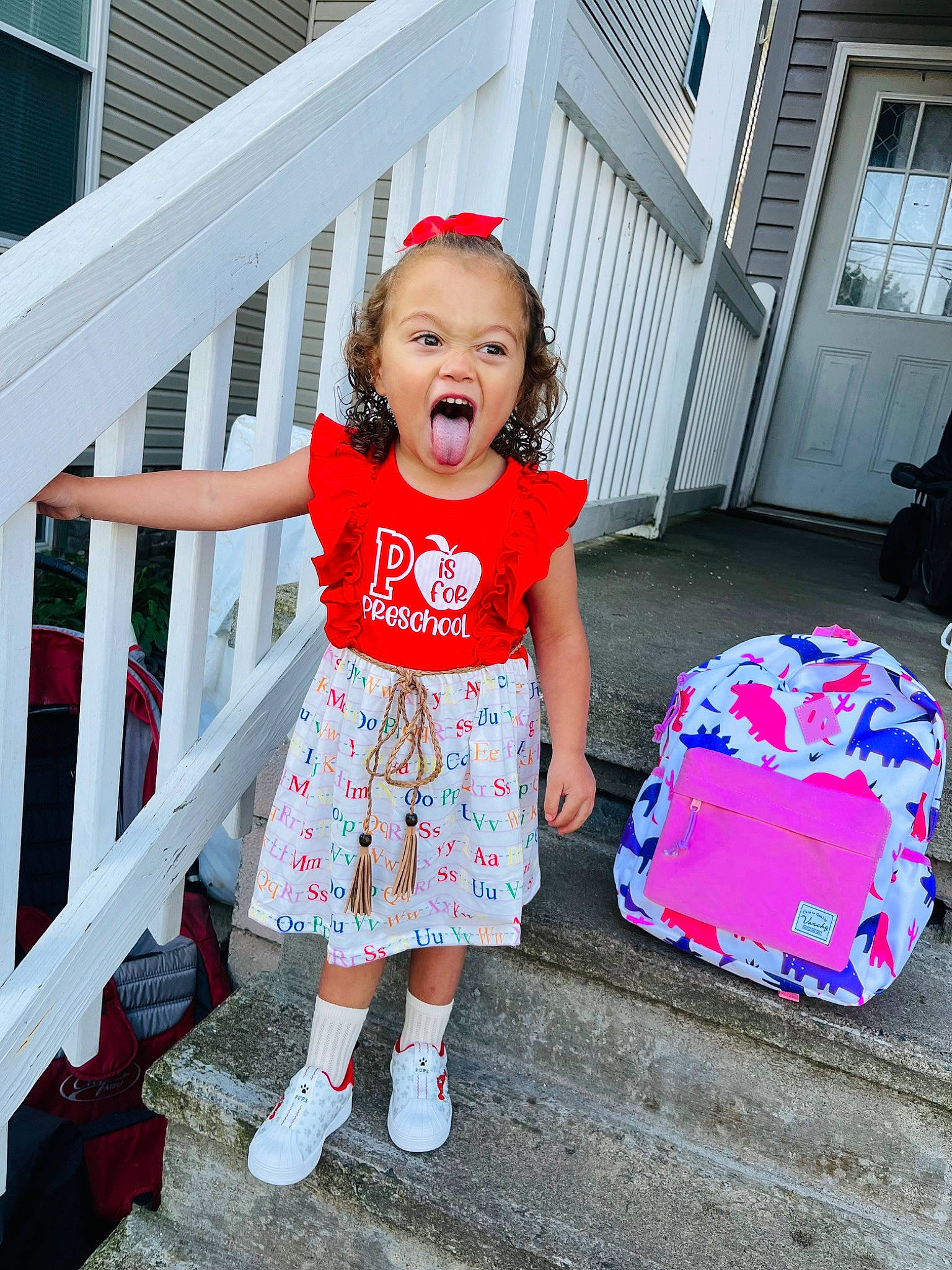 Blakelyn is registered to the contest to win money with this photo: baby_toddler_clothing, child, door, event, fashion, fun, happy, holiday, magenta, pattern, person, pink, porch, red, sandal, sleeve, standing, summer, textile, toddler