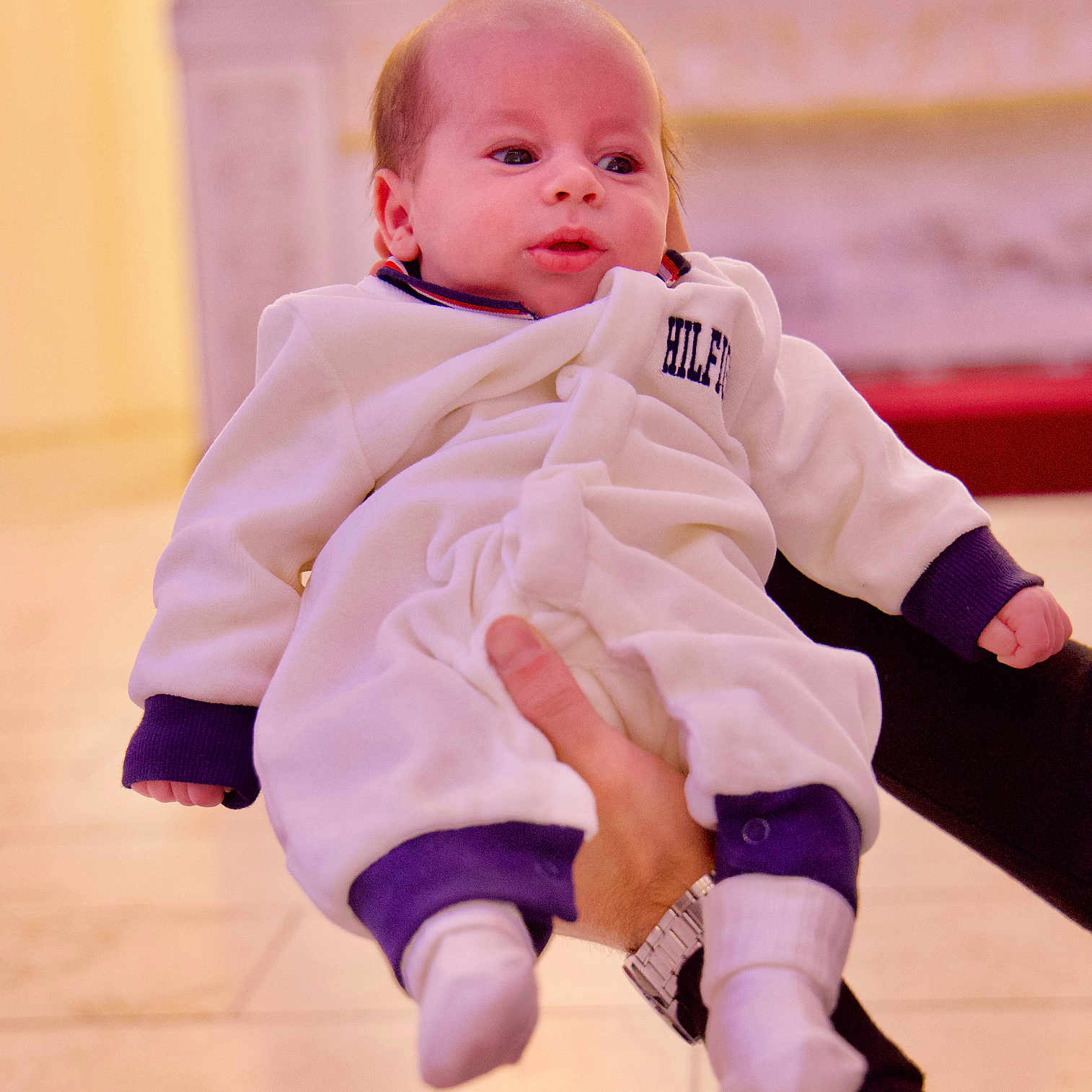 Aren joined the competition — help win amazing prizes! baby, background, child, clothing, cute, expression, face, floor, hand, holding, indoor, infant, newborn, person, portrait, purple_cuffs, socks, warm_lighting, watch, white_outfit
