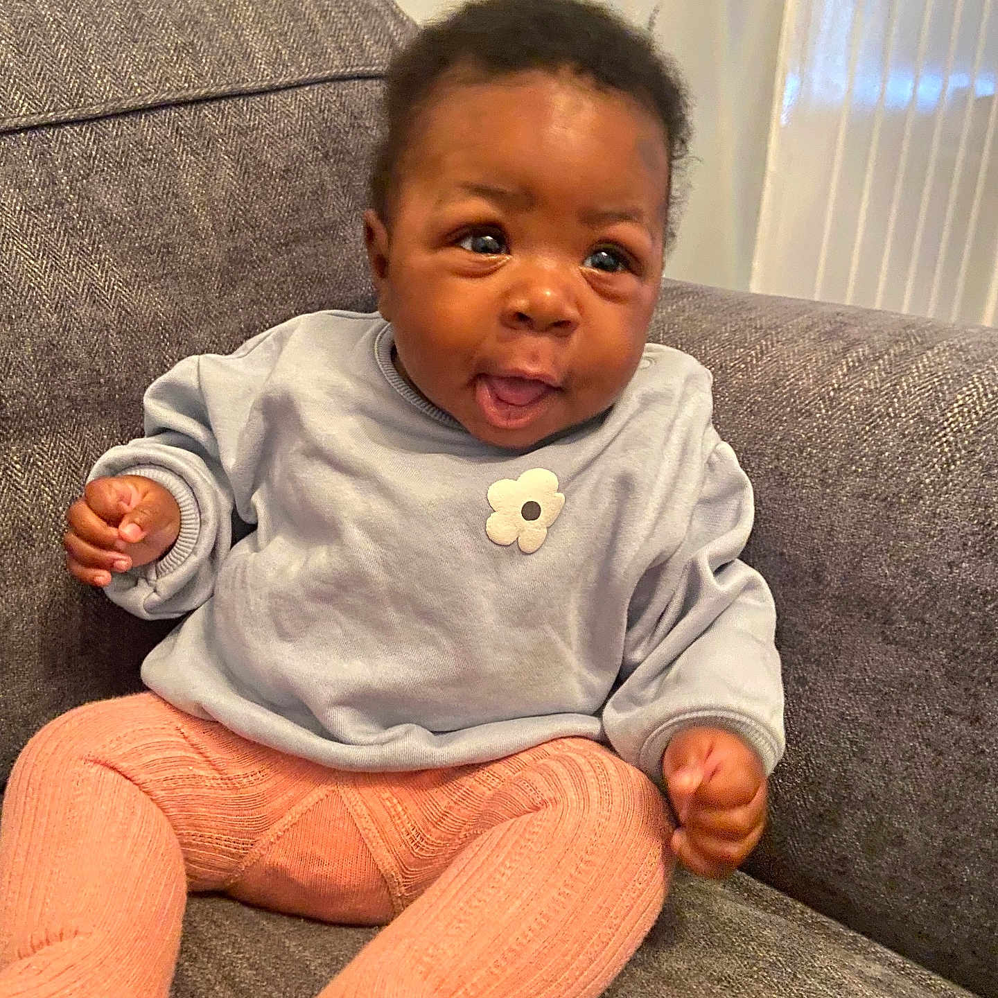 Leah-Eunice joined the competition — help win amazing prizes! baby, child, couch, cozy, cute, flower, furniture, gray_couch, happy, indoor, infant, knitted_tights, light_blue, peach_color, person, portrait, seated, smiling, sweater, young_child