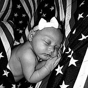 Annmarrie is registered to the contest to win money with this photo: baby, infant, sleeping, bow, headband, black_and_white, american_flag, stars, stripes, fabric, portrait, peaceful, cute, closeup, skin, hand, face, newborn, resting, soft