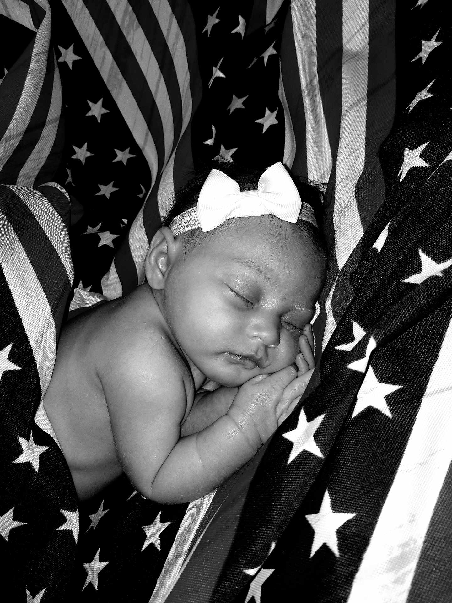 Annmarrie is registered to the contest to win money with this photo: baby, infant, sleeping, bow, headband, black_and_white, american_flag, stars, stripes, fabric, portrait, peaceful, cute, closeup, skin, hand, face, newborn, resting, soft